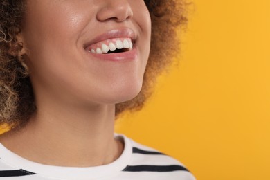 Photo of Woman with clean teeth smiling on yellow background, closeup. Space for text