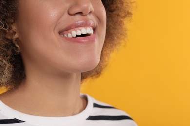 Woman with clean teeth smiling on yellow background, closeup. Space for text