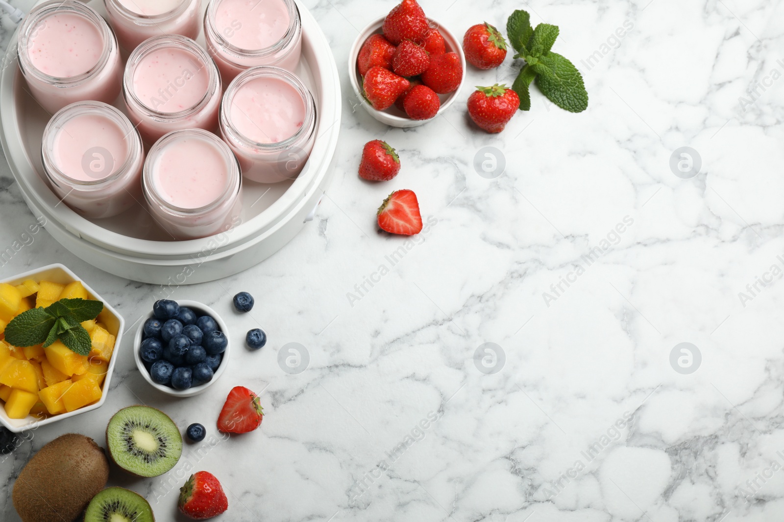 Photo of Modern yogurt maker with full jars and different fruits on white marble table, flat lay. Space for text