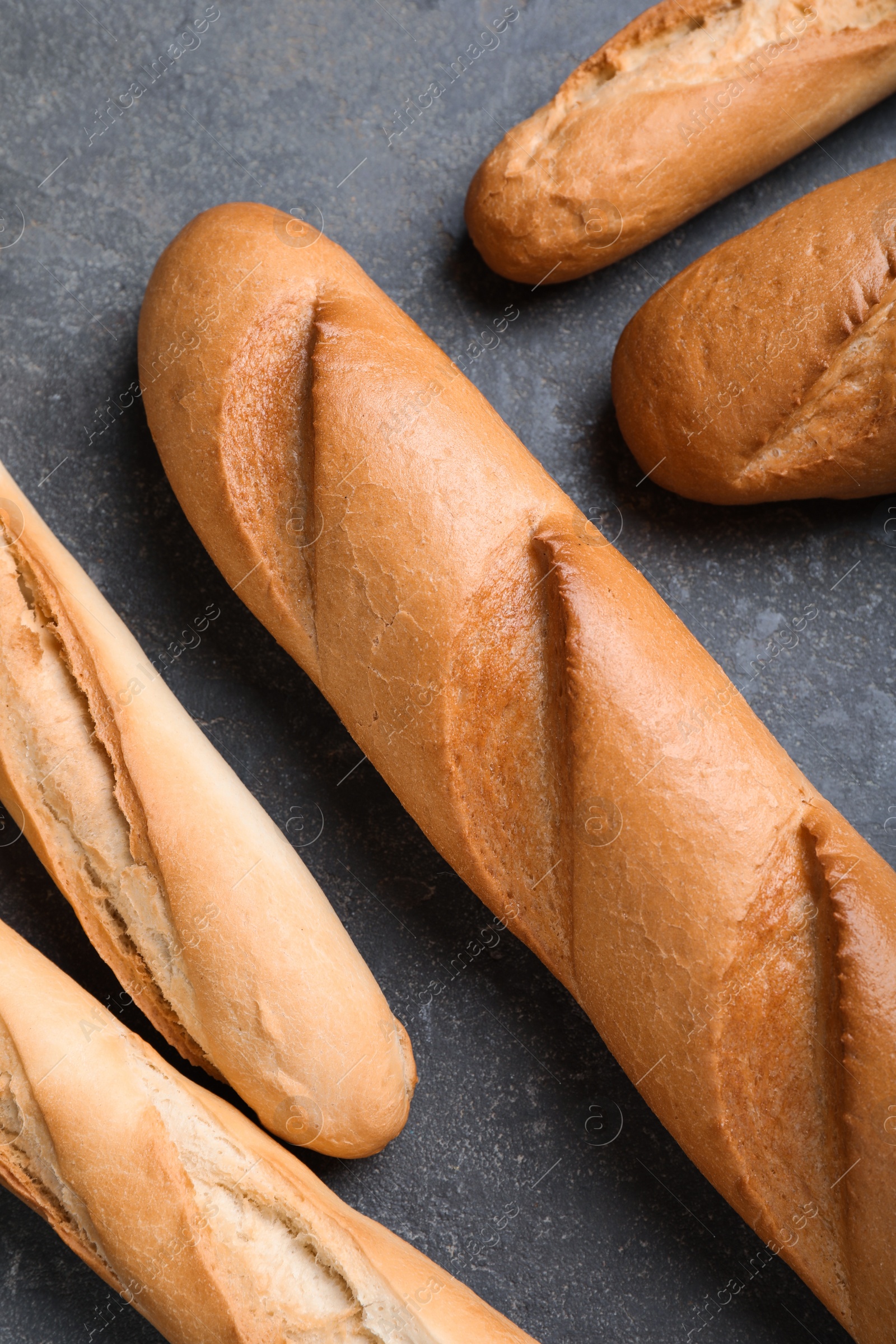 Photo of Different tasty baguettes on grey table, flat lay