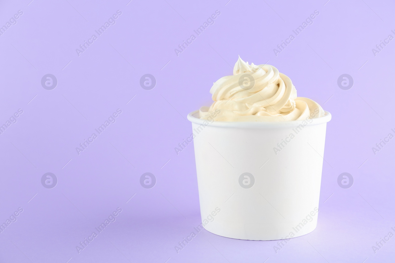 Photo of Cup with tasty frozen yogurt on violet background. Space for text