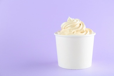 Cup with tasty frozen yogurt on violet background. Space for text