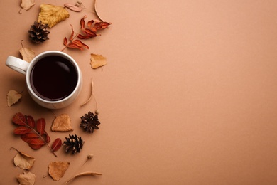 Photo of Flat lay composition with cup of hot drink and autumn leaves on brown background, space for text. Cozy atmosphere