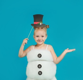 Image of Cute little girl dressed as snowman on light blue background. Christmas suit