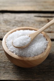 Photo of Organic salt in bowl and spoon on wooden table, closeup