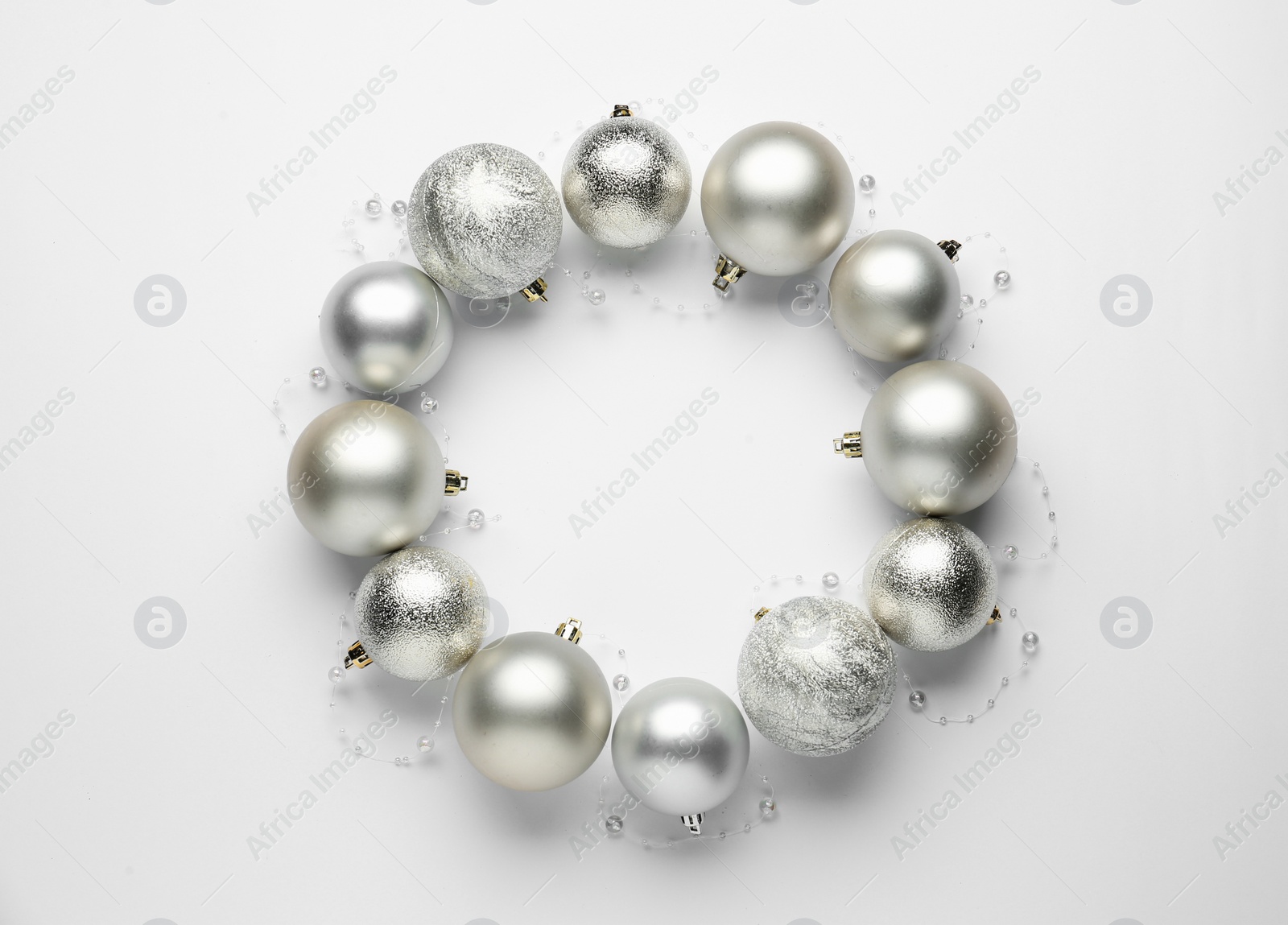 Photo of Beautiful festive wreath made of silver Christmas balls on white background, top view