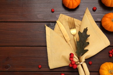 Photo of Cutlery, napkin and autumn decoration on wooden background, flat lay with space for text. Table setting