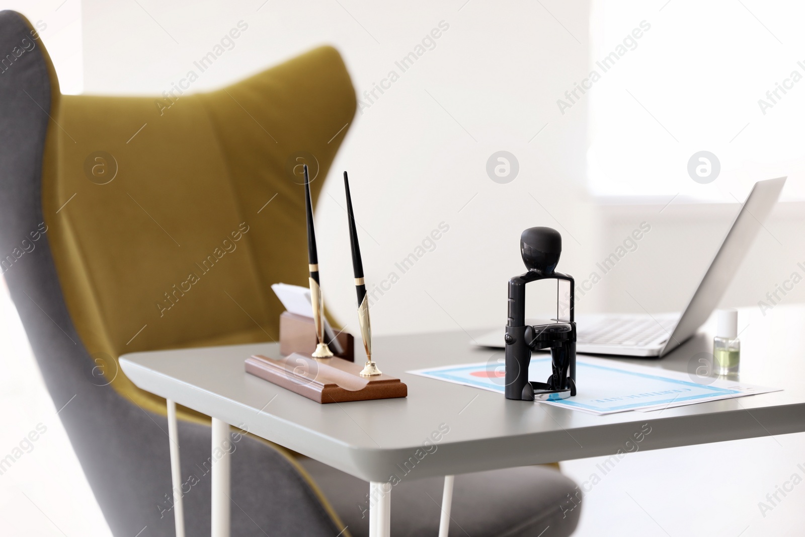 Photo of Automatic stamp, laptop and documents on desk in notary's office