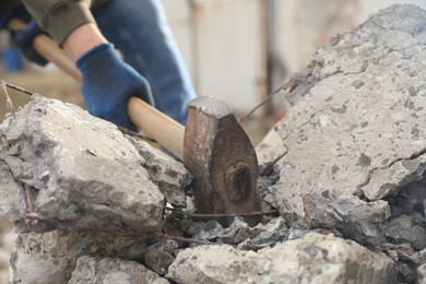 Man breaking stones with sledgehammer outdoors, closeup