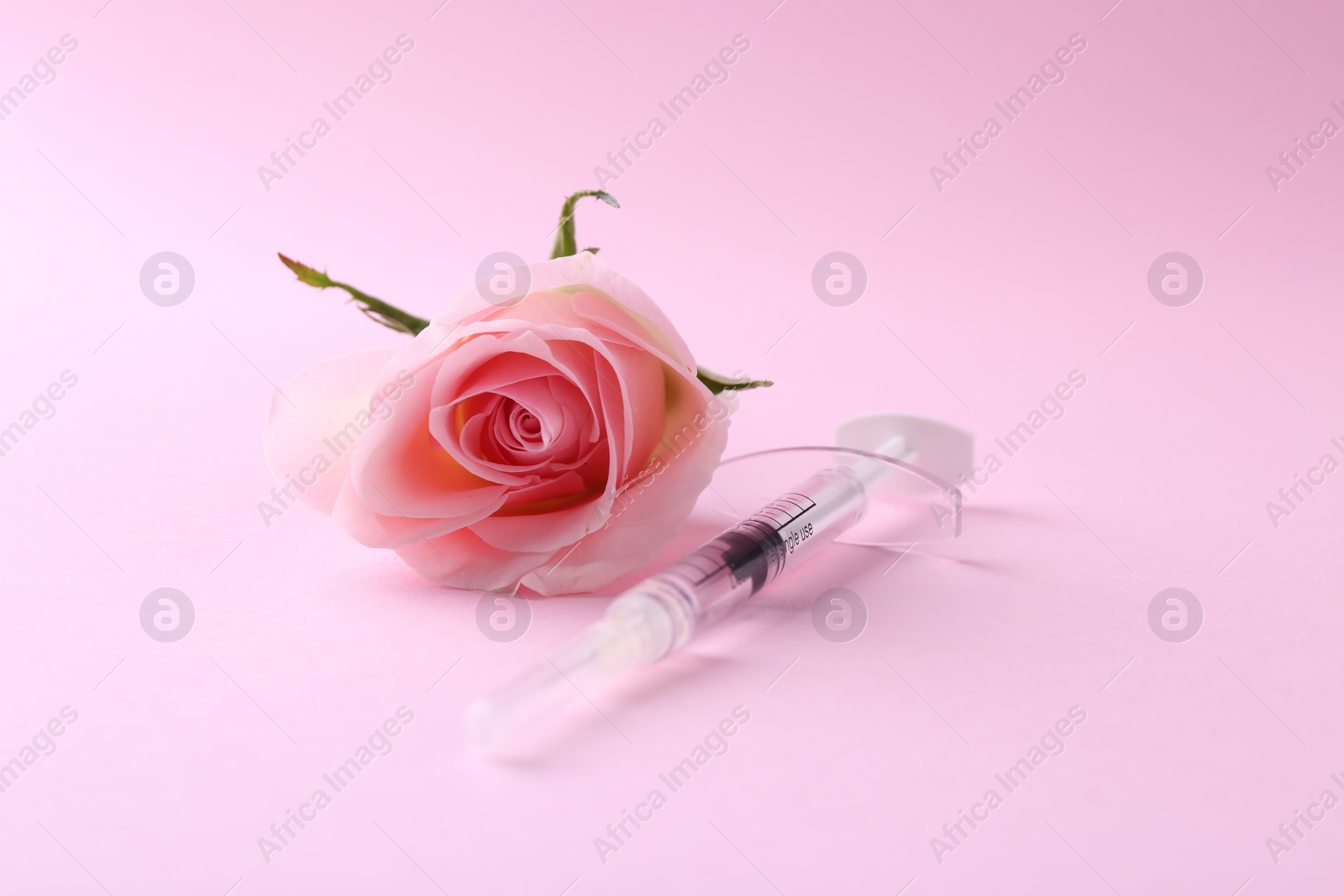 Photo of Cosmetology. Medical syringe and rose flower on pink background