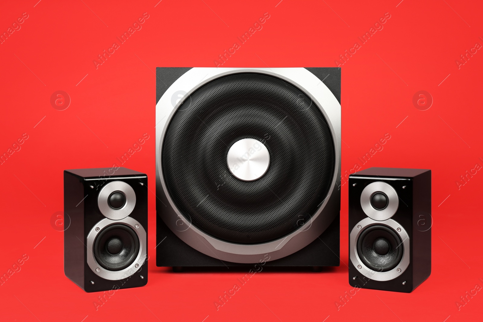 Photo of Modern powerful audio speaker system on red background