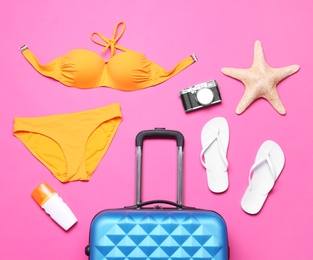 Photo of Flat lay composition with suitcase and beach objects on pink background