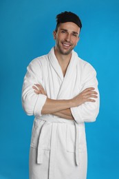Photo of Happy young man in bathrobe on light blue background