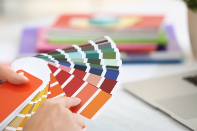 Woman with paint color palette samples at table, closeup