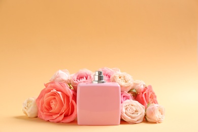 Photo of Bottle of perfume with beautiful roses on color background