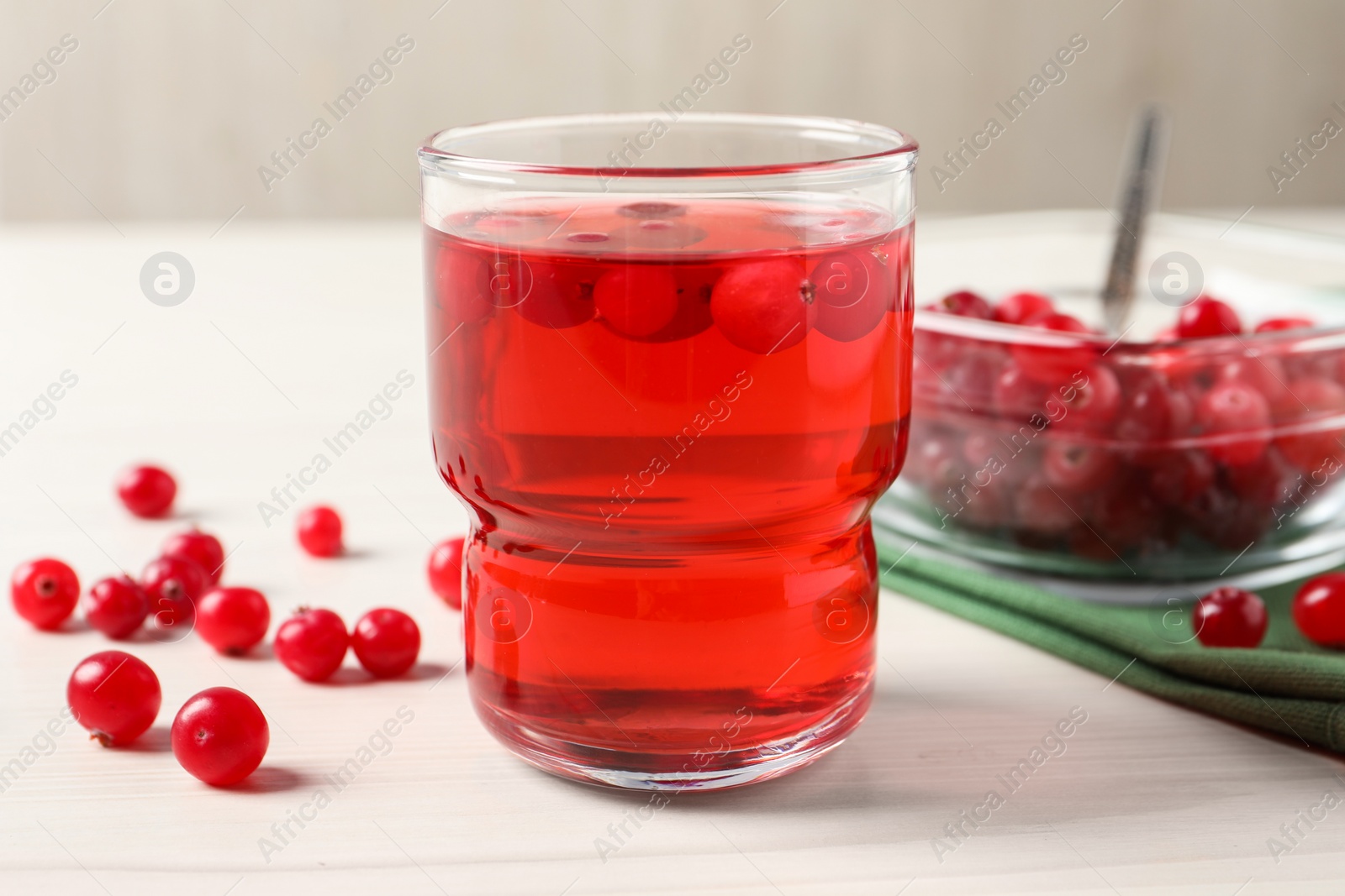 Photo of Tasty cranberry juice in glass and fresh berries on white wooden table, closeup