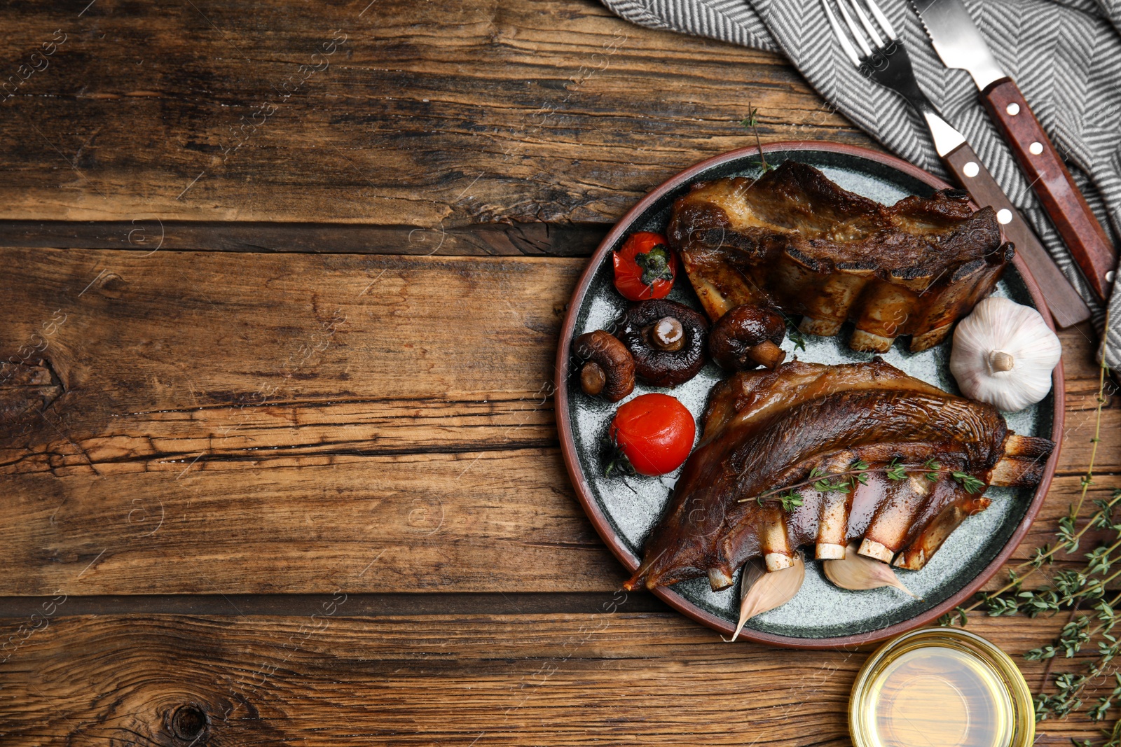 Photo of Delicious roasted ribs served on wooden table, flat lay. Space for text