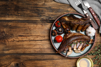 Photo of Delicious roasted ribs served on wooden table, flat lay. Space for text