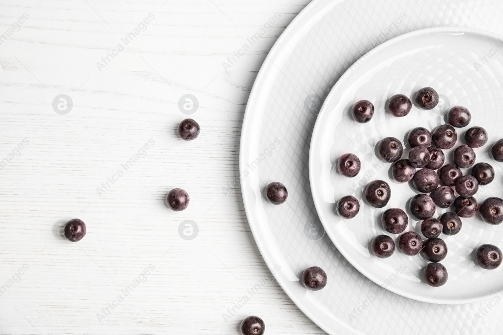 Photo of Plates with fresh acai berries on wooden table, top view