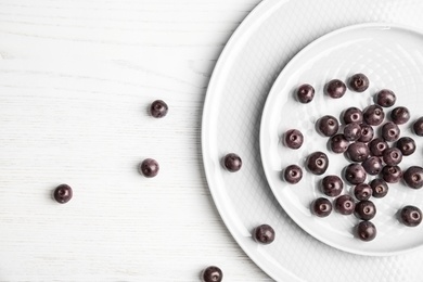 Photo of Plates with fresh acai berries on wooden table, top view