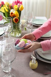 Photo of Woman setting table for festive Easter dinner at home, closeup