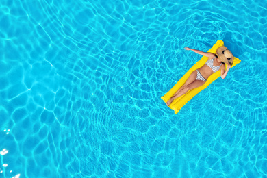 Young woman with inflatable mattress in swimming pool, top view. Space for text