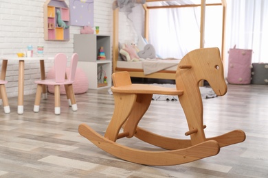Modern wooden rocking horse in playroom. Interior design