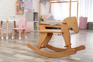 Photo of Modern wooden rocking horse in playroom. Interior design