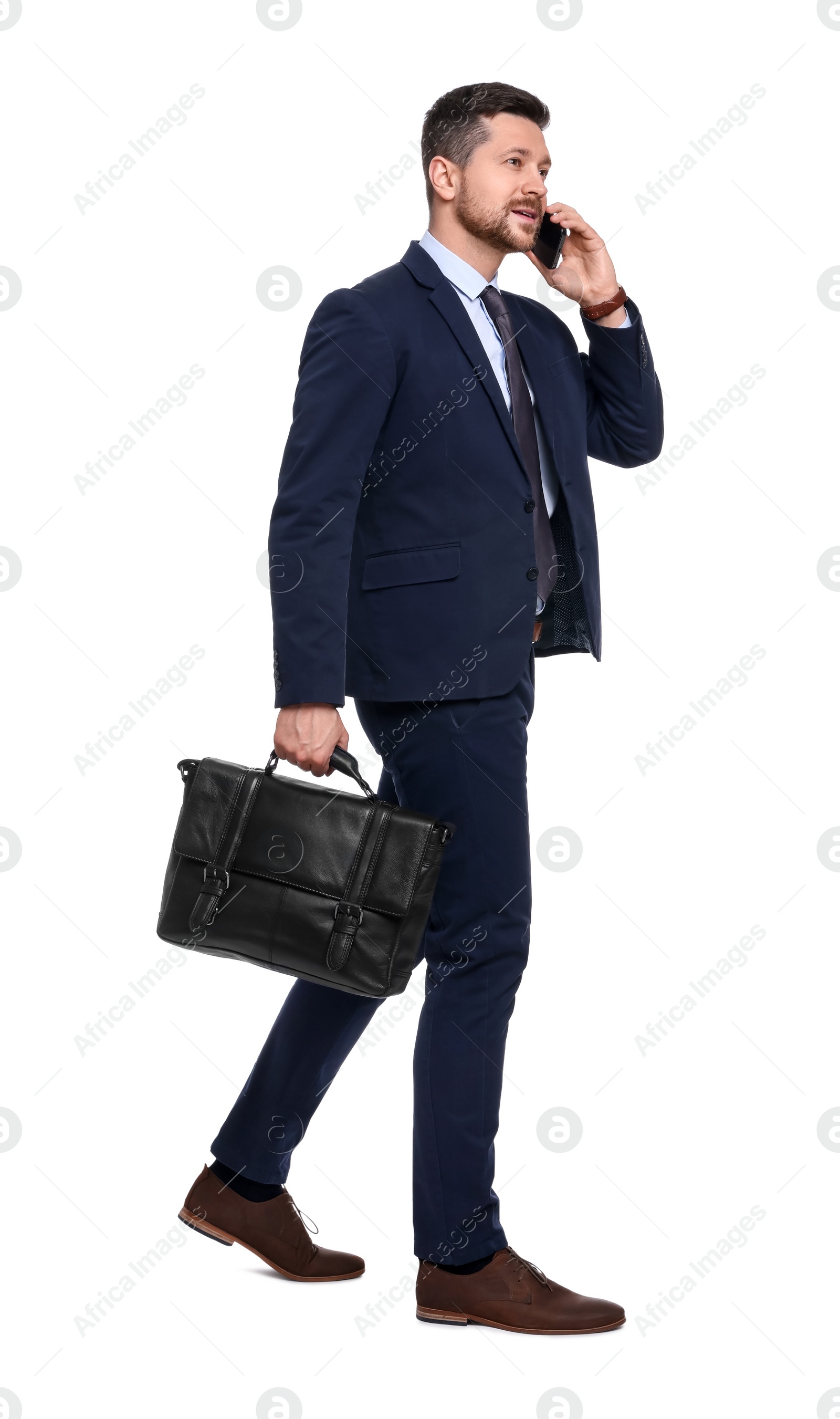 Photo of Handsome bearded businessman in suit with briefcase talking on smartphone against white background