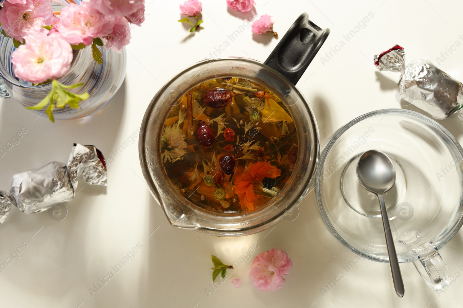 Photo of Flat lay composition with freshly brewed tea and beautiful flowers on light table