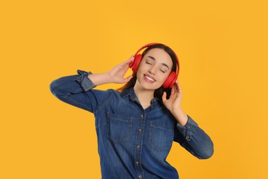 Photo of Happy woman in headphones listening music on orange background