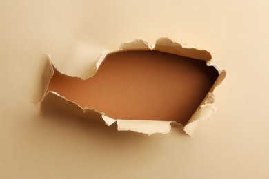 Photo of Hole in light beige paper on brown background