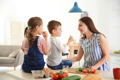 Young woman cooking breakfast for her children in kitchen. Happy family