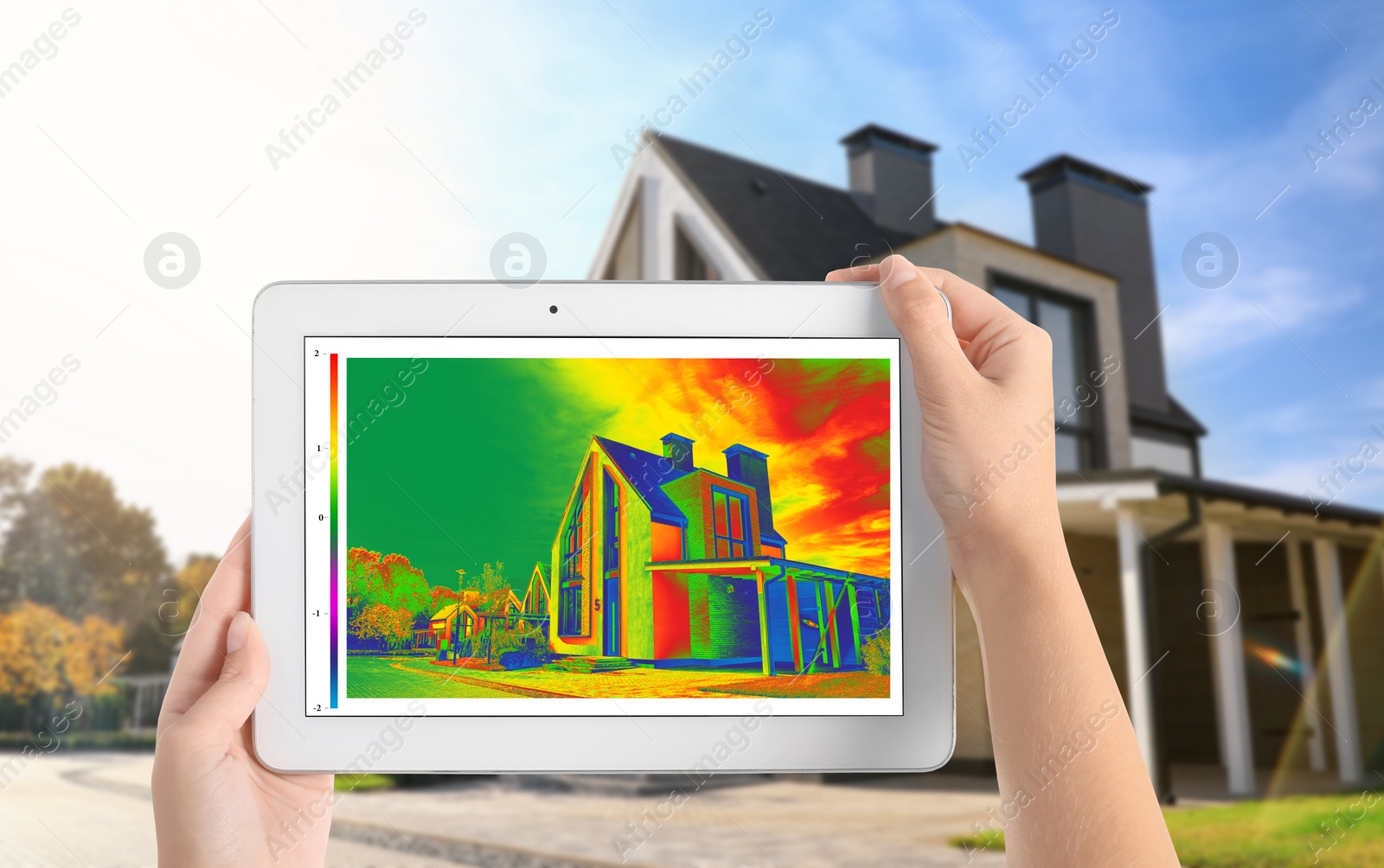 Image of Woman detecting heat loss in house using thermal viewer on tablet, outdoors. Energy efficiency