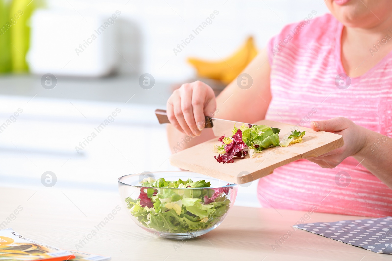 Photo of Overweight woman preparing salad in kitchen, space for text. Healthy diet