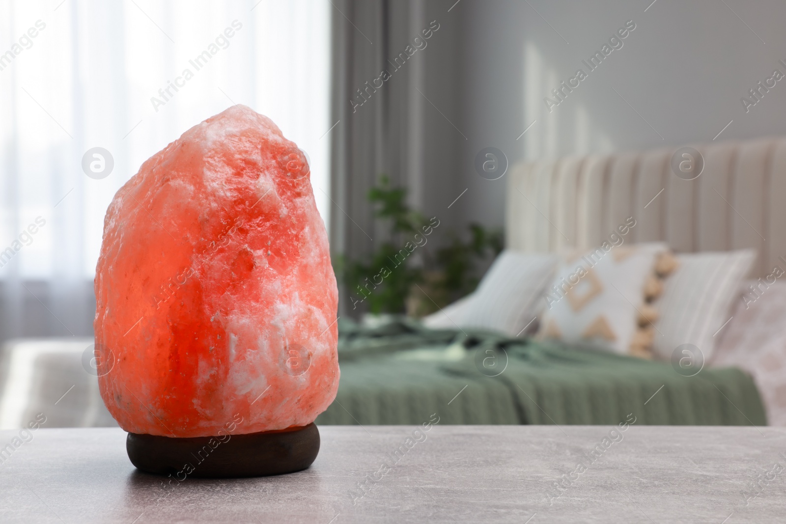 Photo of Beautiful Himalayan salt lamp on light grey table in bedroom, space for text