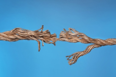 Photo of Frayed rope breaking on color background, closeup