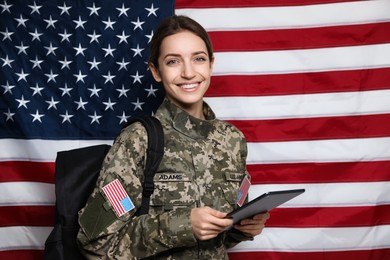 Photo of Female cadet with backpack and tablet against American flag. Military education