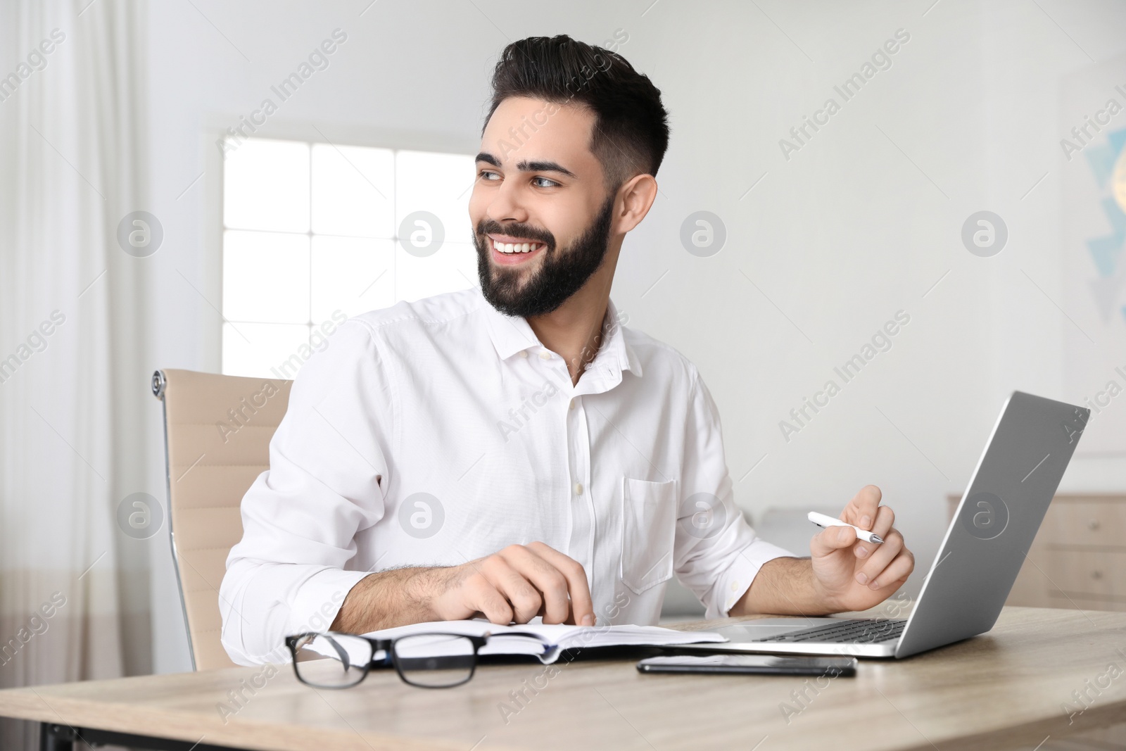 Photo of Handsome young man working at table in home office