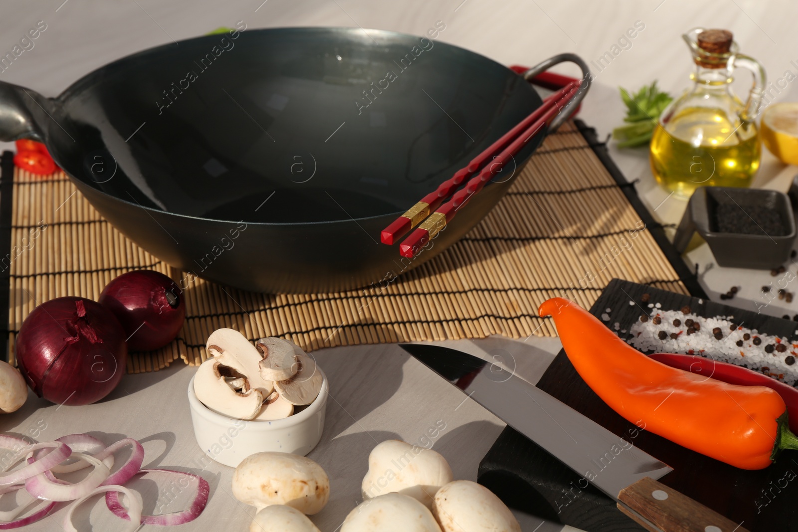 Photo of Wok, chopsticks and different products on white wooden table, closeup