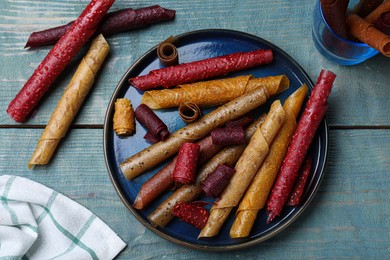 Delicious fruit leather rolls on blue wooden table, flat lay