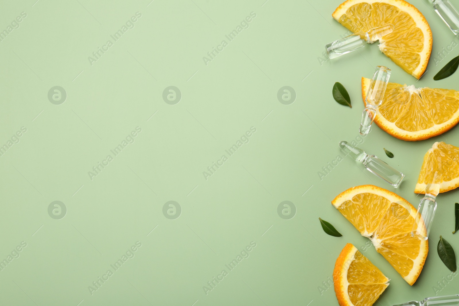 Photo of Skincare ampoules with vitamin C, slices of orange and leaves on light green background, flat lay. Space for text