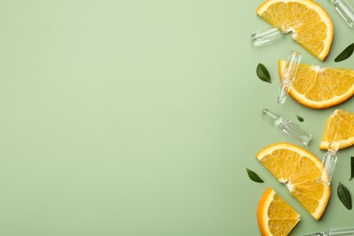 Photo of Skincare ampoules with vitamin C, slices of orange and leaves on light green background, flat lay. Space for text