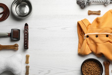 Photo of Flat lay composition with dog clothes, food and accessories on white wooden table. Space for text