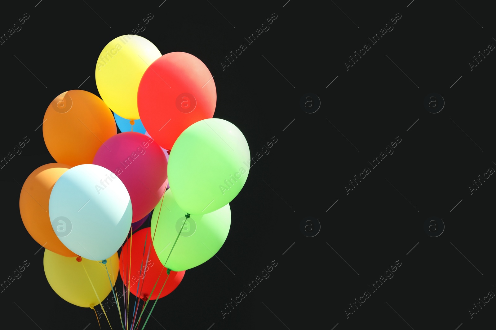 Photo of Bunch of colorful balloons on black background. Space for text