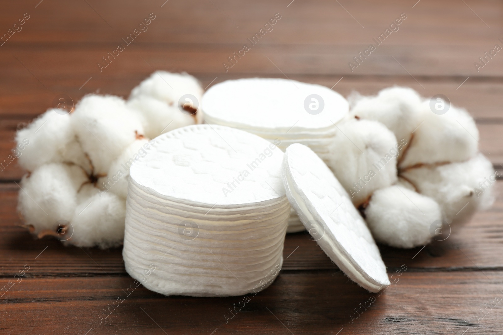 Photo of Composition with cotton pads and flowers on wooden background