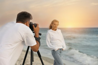 Photo of Photographer taking picture of model with professional camera near sea