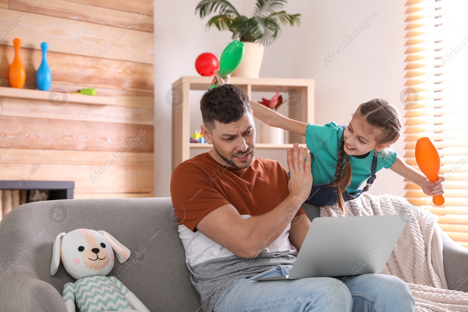 Photo of Cute child disturbing stressed man in living room. Working from home during quarantine