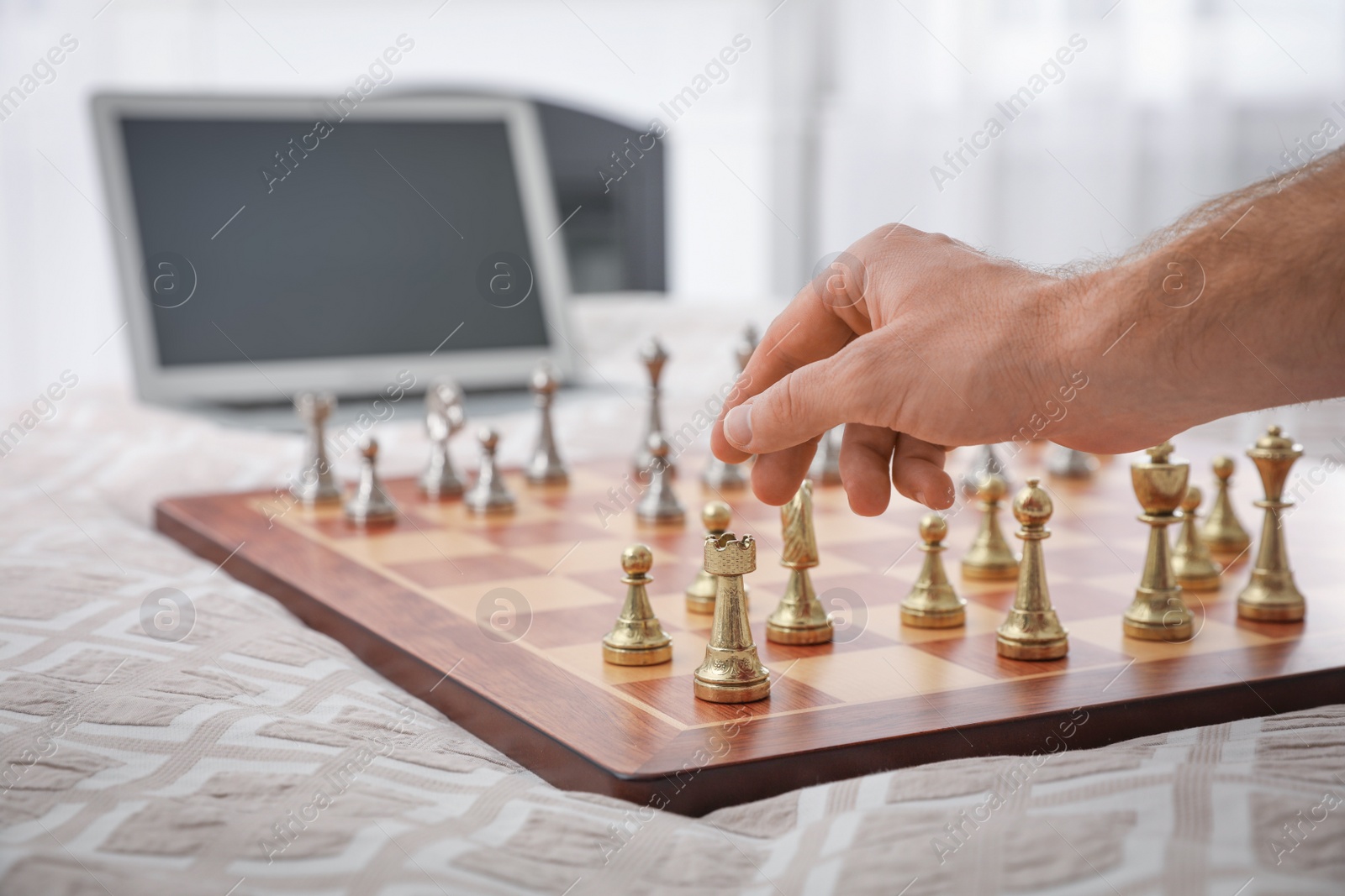 Photo of Man playing chess with partner through online video chat on bed at home, closeup