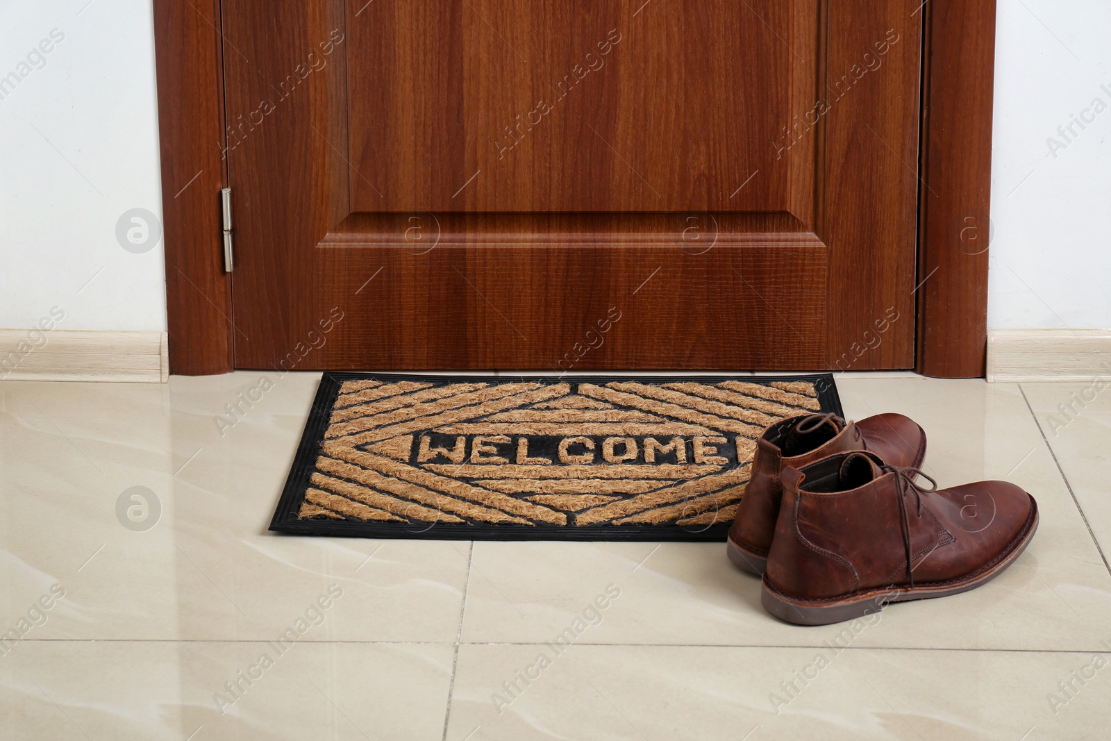 Photo of Brown classic shoes on welcome doormat in hall